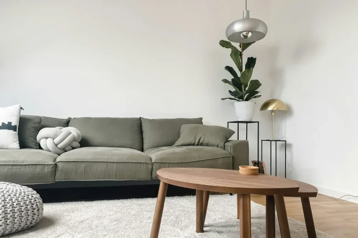 Grey sofa and oval wooden coffee table in a minimal room